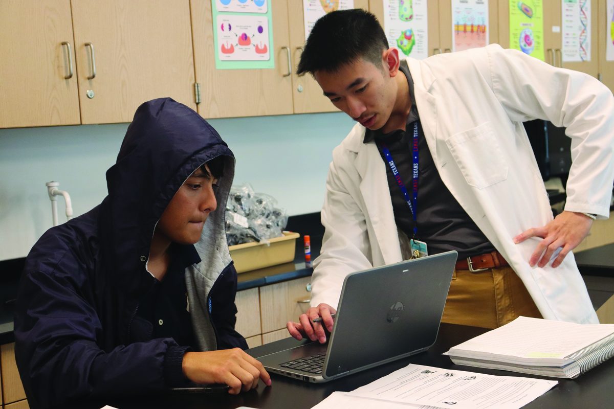 Teacher Ethan Tran assists a student during class on a challenging science concept.